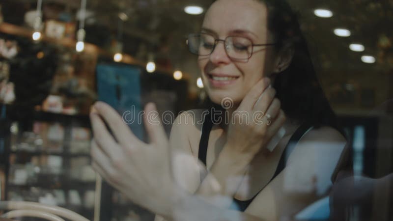 Fermeture d'une femme tenant le téléphone cellulaire dans un caffe. parler à quelqu'un d'aimé sur téléphone portable pendant la pa banque de vidéos