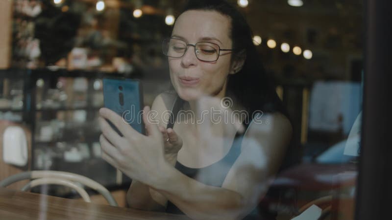 Fermeture d'une femme tenant le téléphone cellulaire dans un caffe. parler à quelqu'un d'aimé sur téléphone portable pendant la pa banque de vidéos