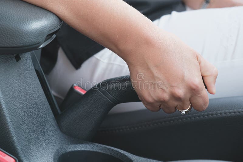 Fermeture d'une femme tirant main levier de frein dans la voiture