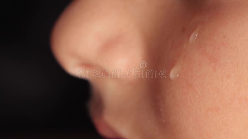 Fermeture d'une joue d'enfant avec une larme glissant vers le bas. une larme tombe lentement sur le visage affligé d'un jeune garç clips vidéos
