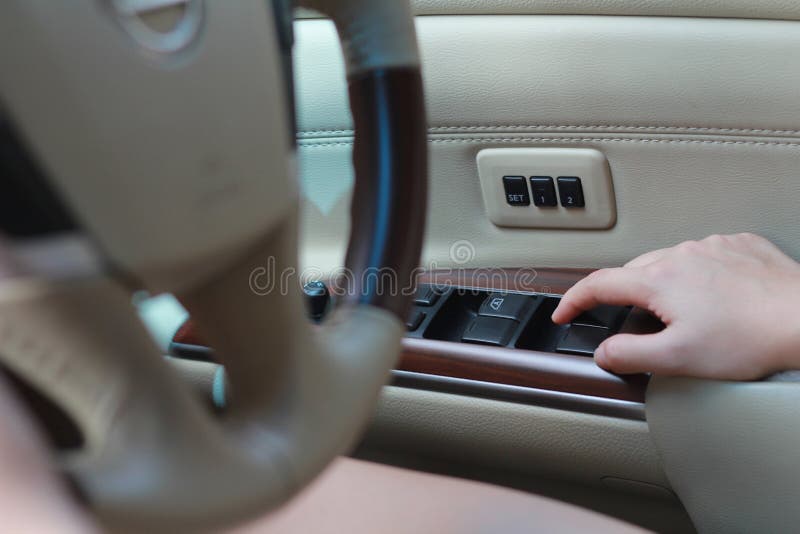 Fermez la main du conducteur de femme en appuyant sur le bouton de la fenêtre de contrôle automatique de l'alimentation dans la v photographie stock Fermez la main du conducteur de femme en appuyant sur le bouton de la fenêtre de contrôle automatique de l'alimentation dans la v photographie stock