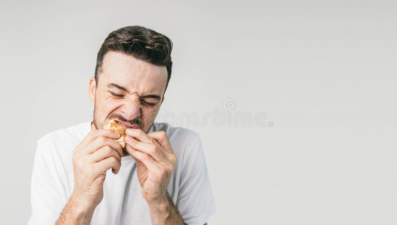 Fermez-vous d'un type dans le chandail blanc stading du côté gauche du cadre et dvouring son hamburger Il le ` s si savoureux il photos libres de droits Fermez-vous d'un type dans le chandail blanc stading du côté gauche du cadre et dvouring son hamburger Il le ` s si savoureux il photos libres de droits
