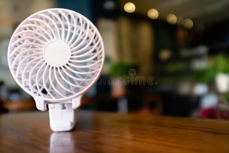 Fermez-vous d'une fan à piles portative, plié sur une table en bois La partie intérieure tourne avec la tache floue de mouvement photographie stock libre de droits Fermez-vous d'une fan à piles portative, plié sur une table en bois La partie intérieure tourne avec la tache floue de mouvement photographie stock libre de droits