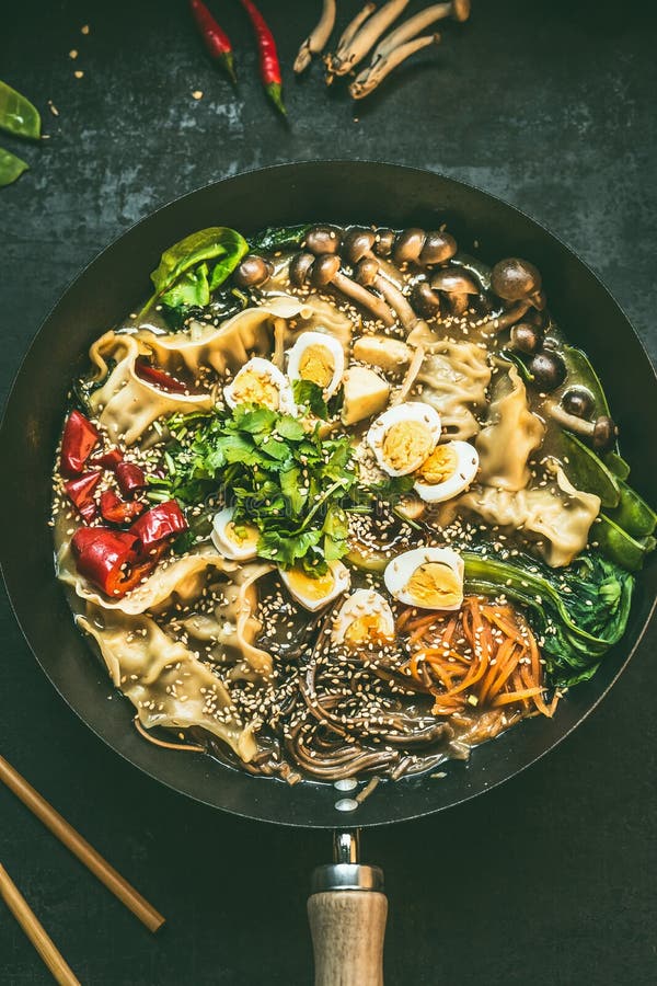 Fermez-vous de la casserole de wok avec le pot et les baguettes chauds coréens végétariens sur le fond rustique foncé de table de photos libres de droits Fermez-vous de la casserole de wok avec le pot et les baguettes chauds coréens végétariens sur le fond rustique foncé de table de photos libres de droits