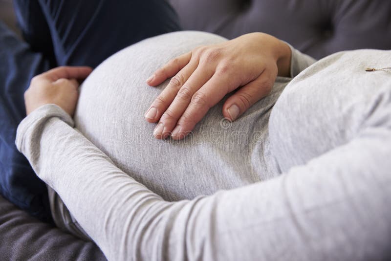 Fermez-vous de la femme enceinte détendant sur le sofa images stock Fermez-vous de la femme enceinte détendant sur le sofa images stock