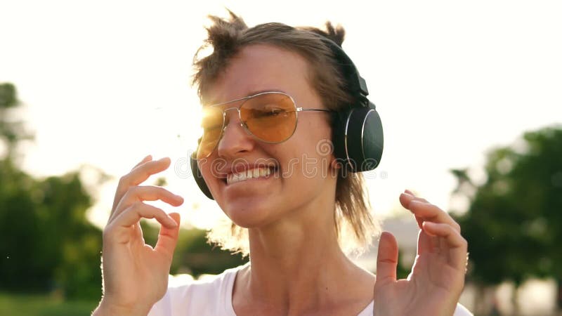 Fermez-vous de la fille juste de cheveux dansant au rythme de la musique avec des écouteurs Vue de face d'une femelle heureuse se banque de vidéos