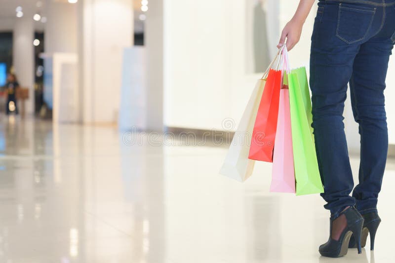 Fermez-vous de la jambe de cliente de femme avec les paniers de papier colorés images stock Fermez-vous de la jambe de cliente de femme avec les paniers de papier colorés images stock