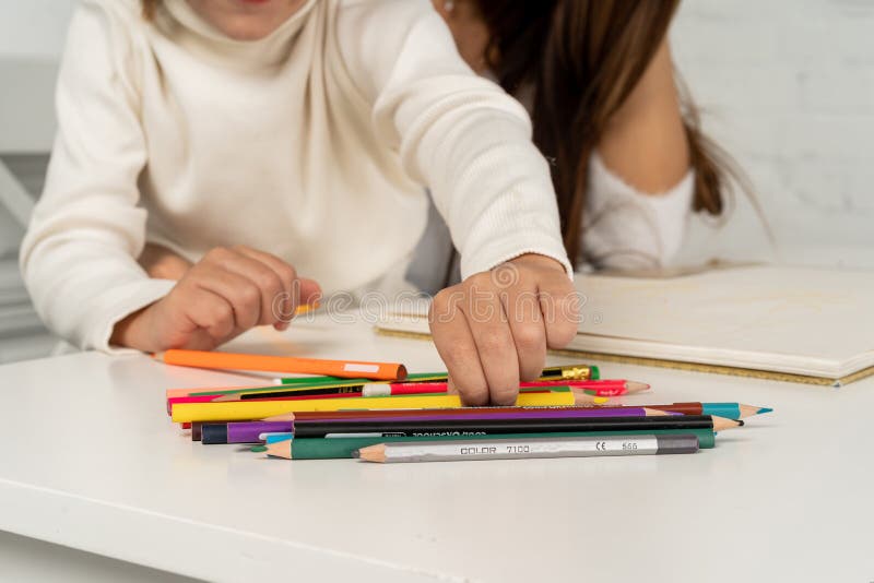 Fermez-vous de la jeune mère heureuse et du petit dessin de fils avec les crayons colorés image stock Fermez-vous de la jeune mère heureuse et du petit dessin de fils avec les crayons colorés image stock