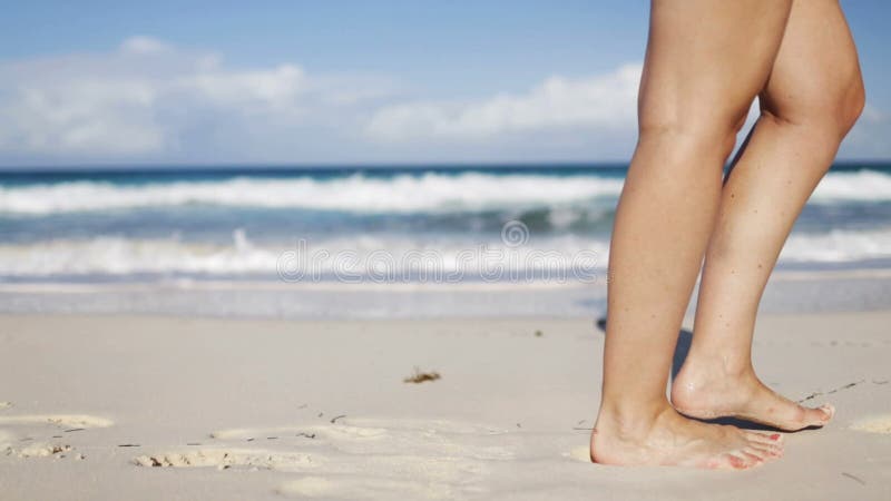 Fermez-vous des jambes de femme marchant sur la plage