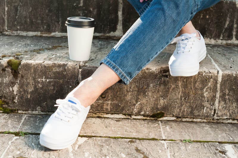 Fermez-vous des jambes et du café femelles sur les escaliers en pierre image libre de droits Fermez-vous des jambes et du café femelles sur les escaliers en pierre image libre de droits