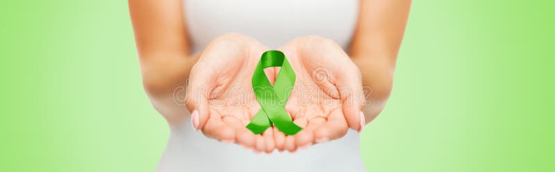 Fermez-vous des mains tenant le ruban vert de conscience photo libre de droits Fermez-vous des mains tenant le ruban vert de conscience photo libre de droits