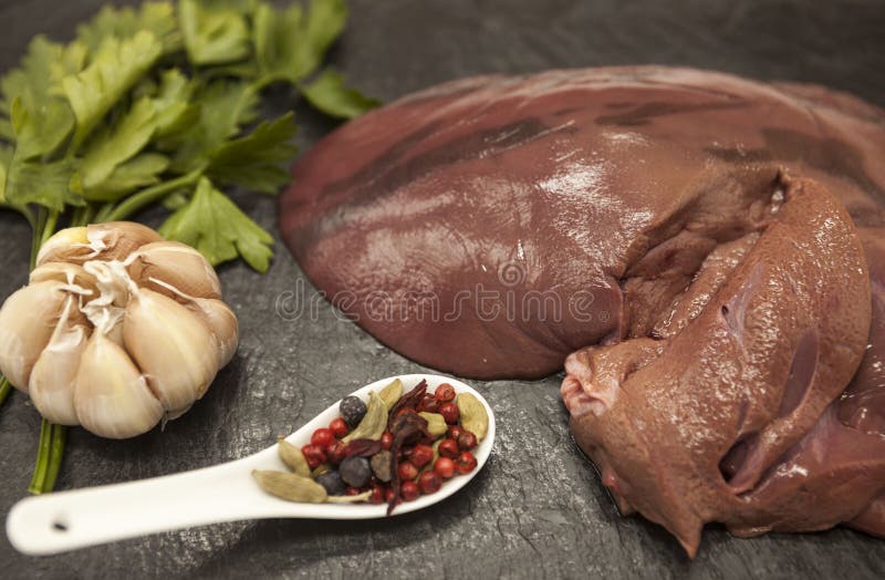 Fermez-vous des morceaux de foie cru frais de boeuf, oignon, ail, les épices, sel du plat en pierre sur un fond blanc images libres de droits Fermez-vous des morceaux de foie cru frais de boeuf, oignon, ail, les épices, sel du plat en pierre sur un fond blanc images libres de droits