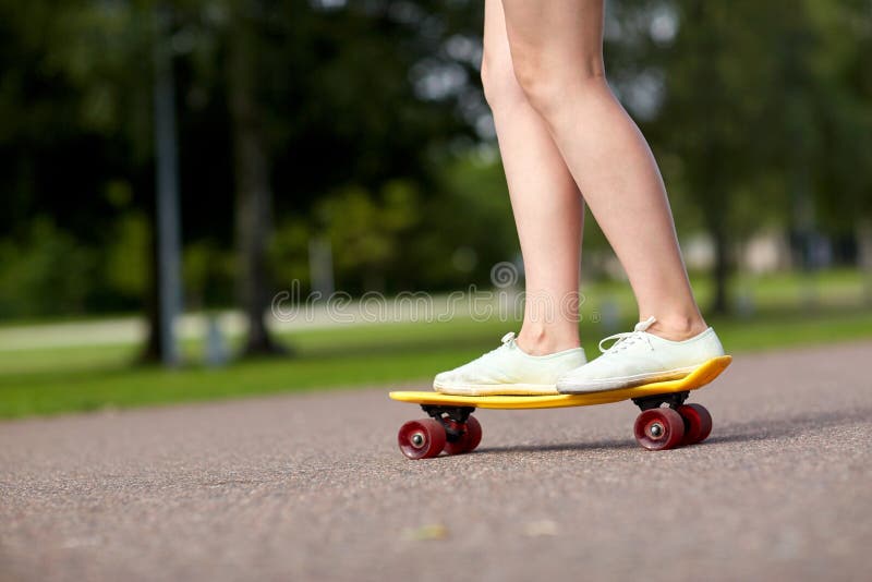 Fermez-vous des pieds femelles montant la planche à roulettes courte image stock Fermez-vous des pieds femelles montant la planche à roulettes courte image stock