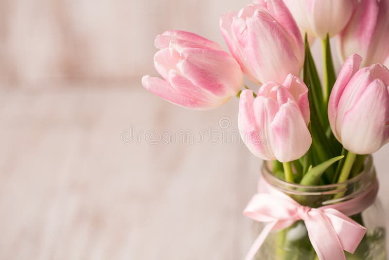 Fermez-vous des tulipes en pastel roses et blanches dans le vase en verre à pot avec image libre de droits