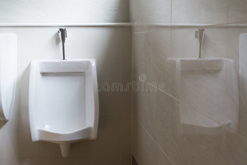 Fermez-vous des urinoirs blancs pour l'homme dans la toilette, toilettes de luxe modernes de conception photographie stock libre de droits Fermez-vous des urinoirs blancs pour l'homme dans la toilette, toilettes de luxe modernes de conception photographie stock libre de droits