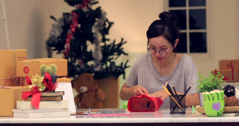 Fermez-vous du boîte-cadeau de déformation de fille mignonne asiatique et d'écrire la carte heureuse avec le visage de sourire banque de vidéos