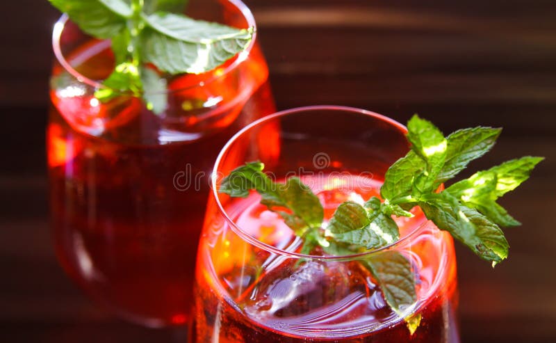 Fermez-vous du cocktail rouge avec les feuilles en bon état vertes de glaçons en verre de vin image libre de droits Fermez-vous du cocktail rouge avec les feuilles en bon état vertes de glaçons en verre de vin image libre de droits