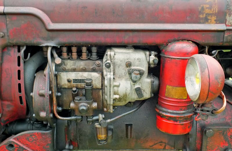 Fermez-vous du moteur d'un vieux tracteur de cru avec la carrosserie et le phare rouill?s rouges images libres de droits Fermez-vous du moteur d'un vieux tracteur de cru avec la carrosserie et le phare rouill?s rouges images libres de droits