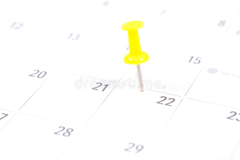 Fermez-vous vers le haut de la goupille jaune sur le calendrier blanc image stock Fermez-vous vers le haut de la goupille jaune sur le calendrier blanc image stock