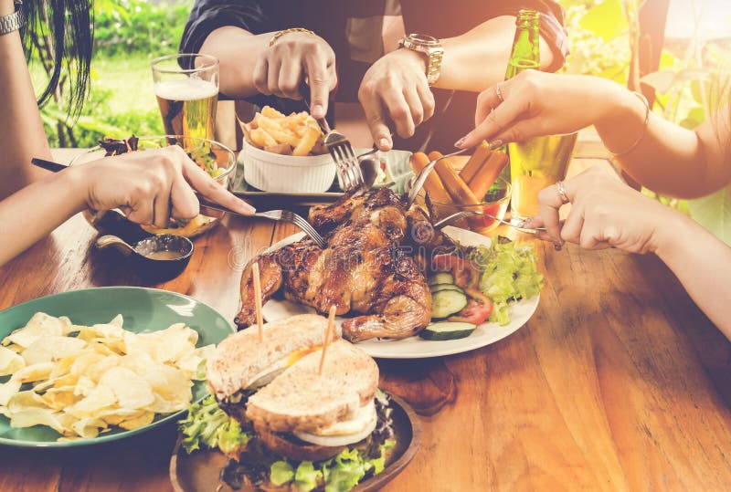 Close up hand, eating.Group Of People Dining Concept,With Chicken roasting,salad,French fries on wood table. Close up hand, eating.Group Of People Dining Concept,With Chicken roasting,salad,French fries on wood table