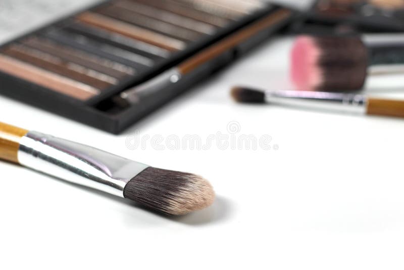 Fermez-vous vers le haut des brosses de maquillage avec la palette de fards à paupières et le fond de brosses image libre de droits Fermez-vous vers le haut des brosses de maquillage avec la palette de fards à paupières et le fond de brosses image libre de droits