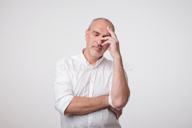 Fermez-vous vers le haut du portrait de l'homme mûr bel dans la chemise blanche tenant la main près du visage et pensant au trava photographie stock libre de droits Fermez-vous vers le haut du portrait de l'homme mûr bel dans la chemise blanche tenant la main près du visage et pensant au trava photographie stock libre de droits
