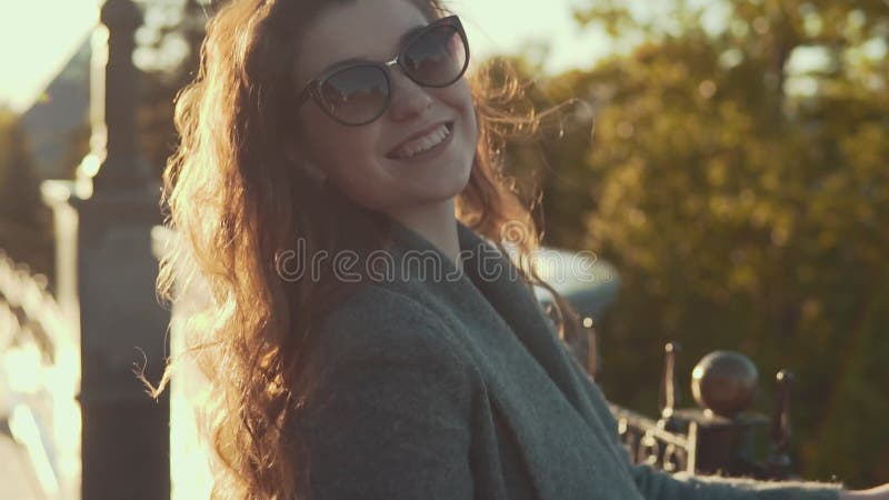 Fermez-vous vers le haut du portrait de la femme mignonne à la mode dans des lunettes de soleil dans les rayons du soleil banque de vidéos