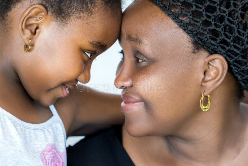 Close up face shot of african mother and little daughter joining heads. Mother and child showing affection isolated on white background. Close up face shot of african mother and little daughter joining heads. Mother and child showing affection isolated on white background.