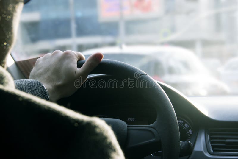 Close up shot of a man`s hands holding a car`s steering wheel.Driving safety in the city. Close up shot of a man`s hands holding a car`s steering wheel.Driving safety in the city.