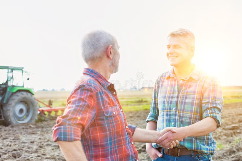 Fermierii care își strâng mâna după acordul cu combinațiile de recoltare pe teren stock photography