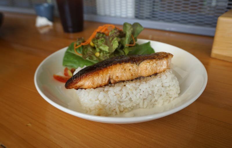 Fermé des saumons Grilled avec de la sauce à teriyaki sur le riz japonais servant avec de la salade fraîche image stock Fermé des saumons Grilled avec de la sauce à teriyaki sur le riz japonais servant avec de la salade fraîche image stock