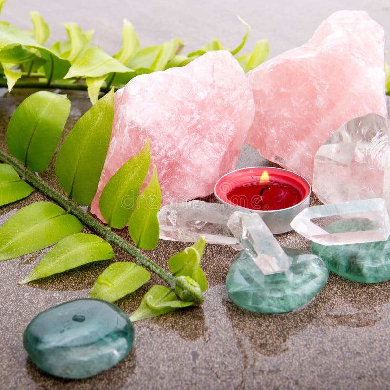 Fern leaf with healing crystals and red candle