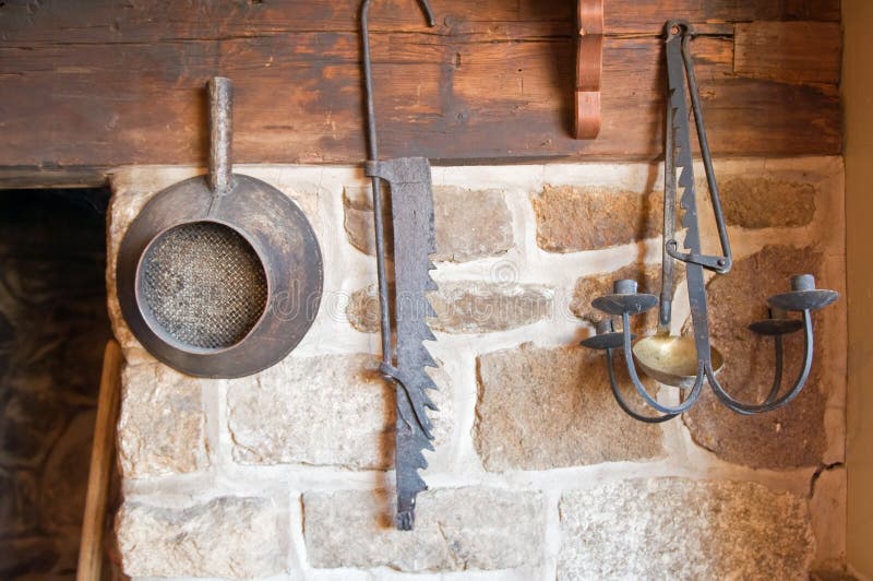 A collection of old antique tools hung in a country kitchen. A collection of old antique tools hung in a country kitchen.