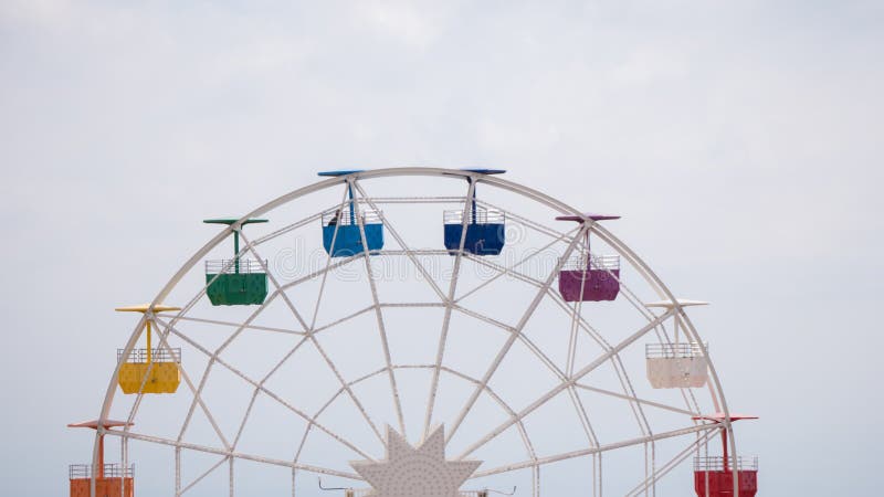 Ferris wheel on cloudy sky background. Rainbow