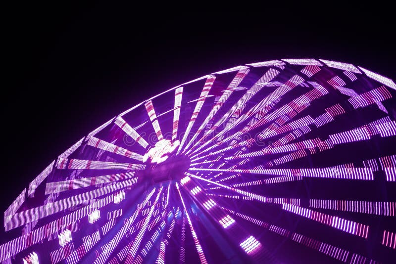 Ferris Wheel in Motion at the Amusement Park, Night Illumination. Long Exposure Stock Photo