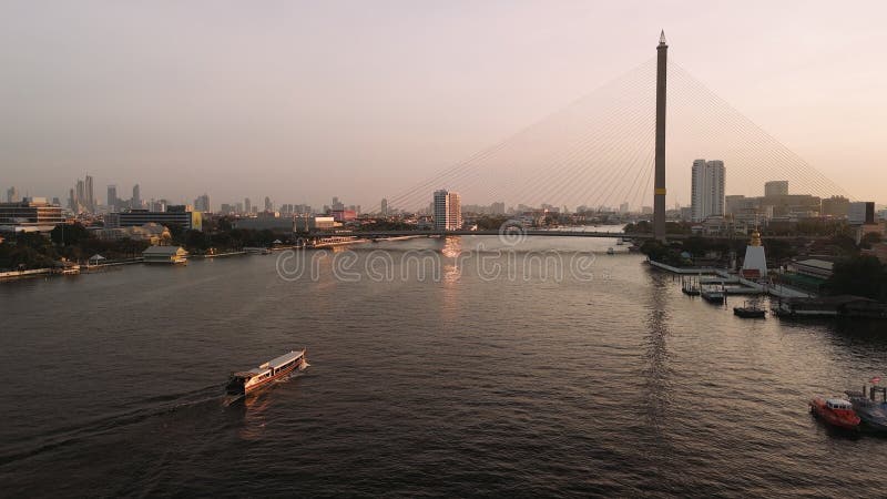 Ferry naviguant le fleuve Chao Phraya au coucher du soleil Rama viii pont Bangkok Thaïlande banque de vidéos