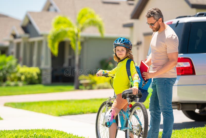 Festa dei padri felici. padre e figlio in casco per aver imparato ad andare in bici al parco. padre che aiuta il figlio a ciclare immagine stock libera da diritti