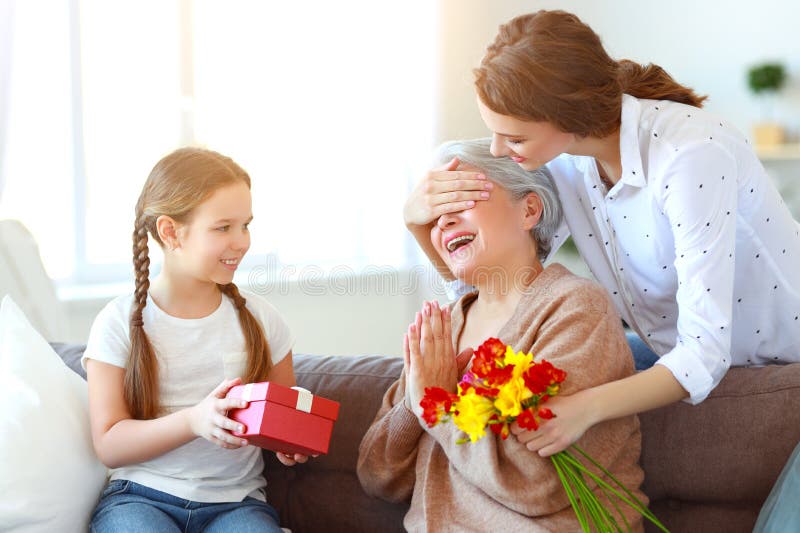 Festa della mamma! tre generazioni di madre, di nonna e di figlia della famiglia si congratulano sulla festa, danno i fiori immagini stock Festa della mamma! tre generazioni di madre, di nonna e di figlia della famiglia si congratulano sulla festa, danno i fiori immagini stock