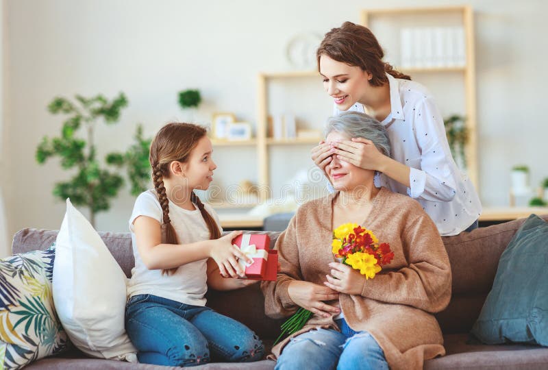 Festa della mamma! tre generazioni di madre, di nonna e di figlia della famiglia si congratulano sulla festa, danno i fiori immagini stock Festa della mamma! tre generazioni di madre, di nonna e di figlia della famiglia si congratulano sulla festa, danno i fiori immagini stock