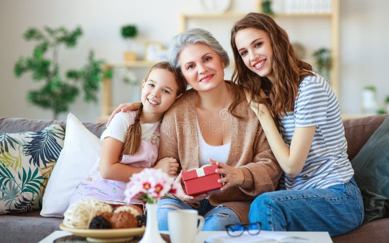 Festa della mamma! tre generazioni di madre, di nonna e di figlia della famiglia si congratulano sulla festa, danno il regalo att fotografie stock libere da diritti Festa della mamma! tre generazioni di madre, di nonna e di figlia della famiglia si congratulano sulla festa, danno il regalo att fotografie stock libere da diritti