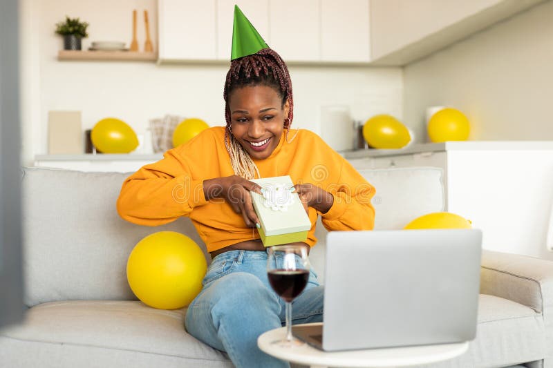 Festa di compleanno online. esaltata donna africana americana che riceve un regalo da amici che festeggiano l'anniversario tramite fotografie stock libere da diritti