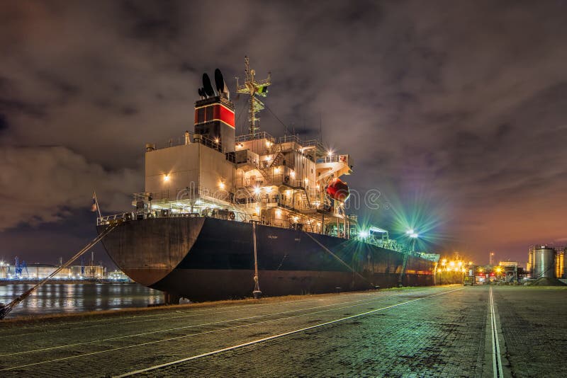 Festgemachter Öltanker nachts mit einem drastischen bewölkten Himmel, Hafen von Antwerpen, Belgien stockbild Festgemachter Öltanker nachts mit einem drastischen bewölkten Himmel, Hafen von Antwerpen, Belgien stockbild
