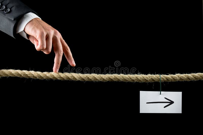 Conceptual image of business determination with a businessman walking his fingers along a length of rope towards a white card with right pointing arrow. Conceptual image of business determination with a businessman walking his fingers along a length of rope towards a white card with right pointing arrow.