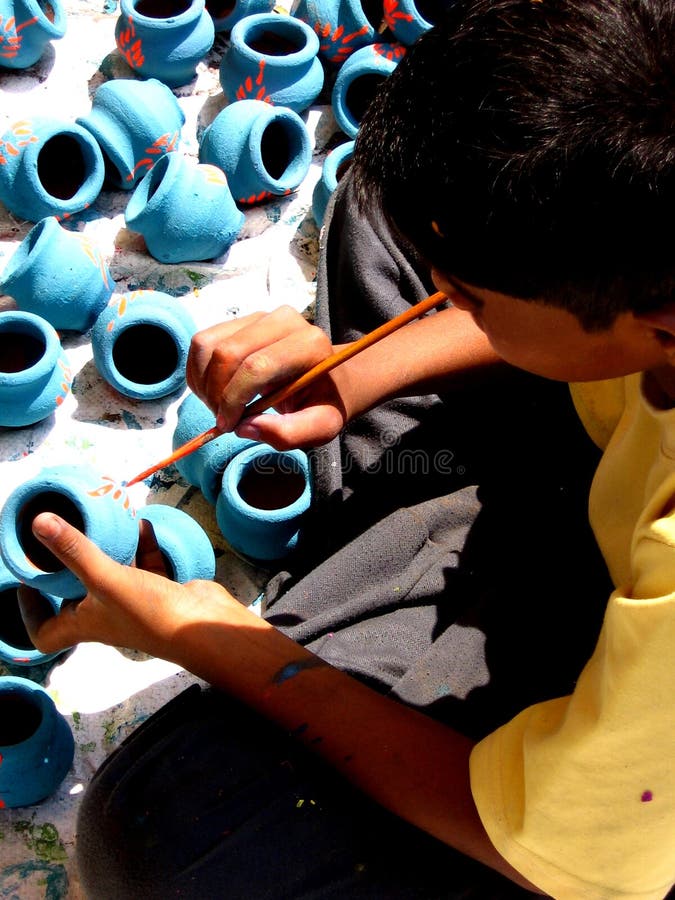 A poor kid paints pots to be sold during diwali festival. A poor kid paints pots to be sold during diwali festival.