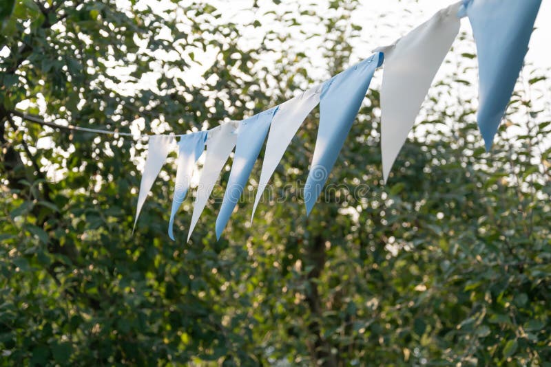 Festive flags garland hanging outdoors in the park or garden stock photos Festive flags garland hanging outdoors in the park or garden stock photos