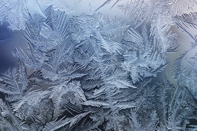 Festive frosty pattern with white snowflakes on a blue background on glass