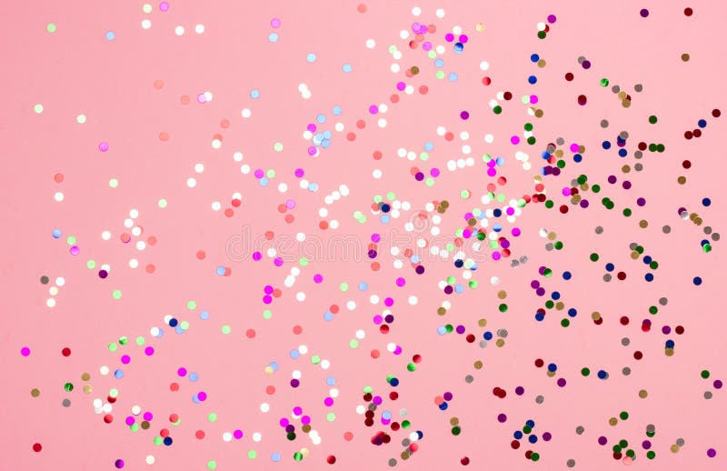 Festive pastel pink background with metallic confetti. 