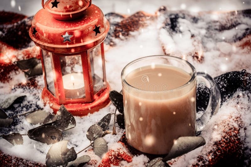 Festive red candle in lantern and mug of coffee on rug with snow