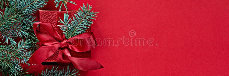 Festive red gift box with fir branches on a red background. Banner with Christmas and New Year concept