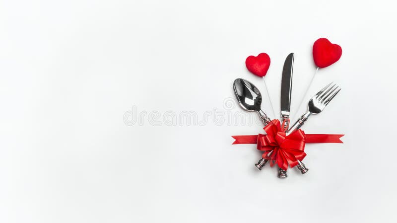 Festive table place setting with red bow , cutlery and two hearts on white background, banner. Layout for Valentines day dinner in